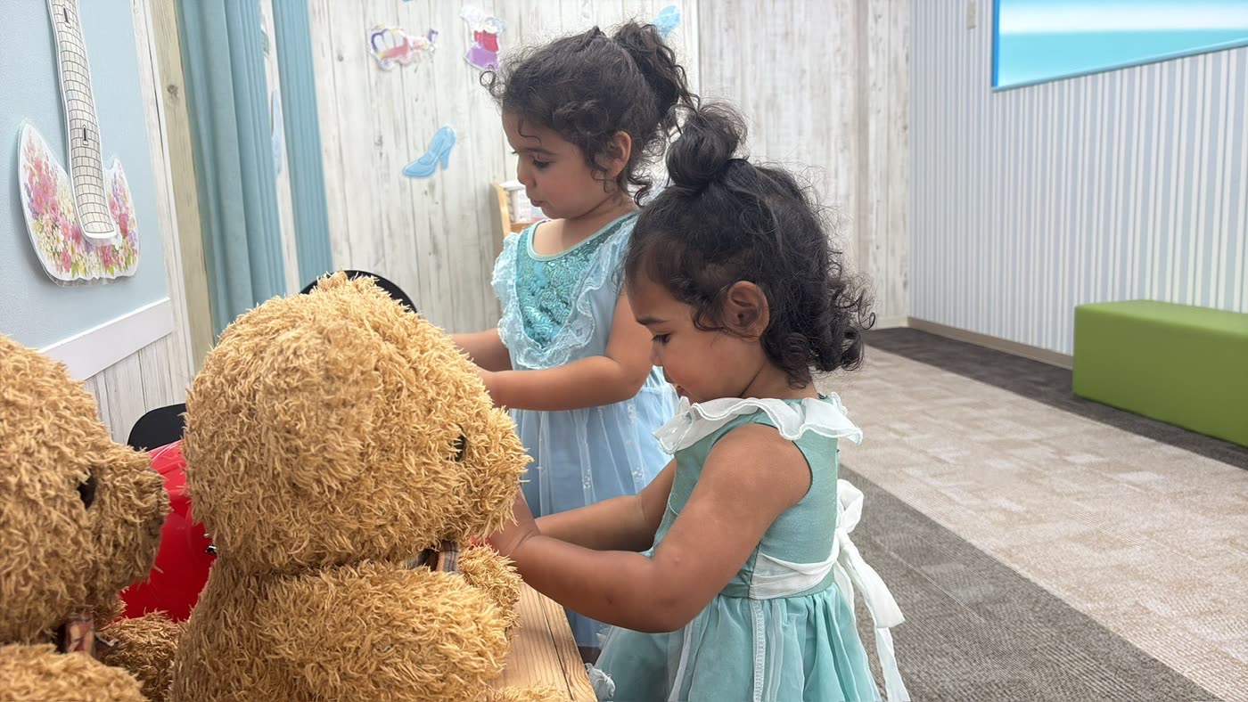 Two girls playing with a teddy bear at a Tokyo studio
